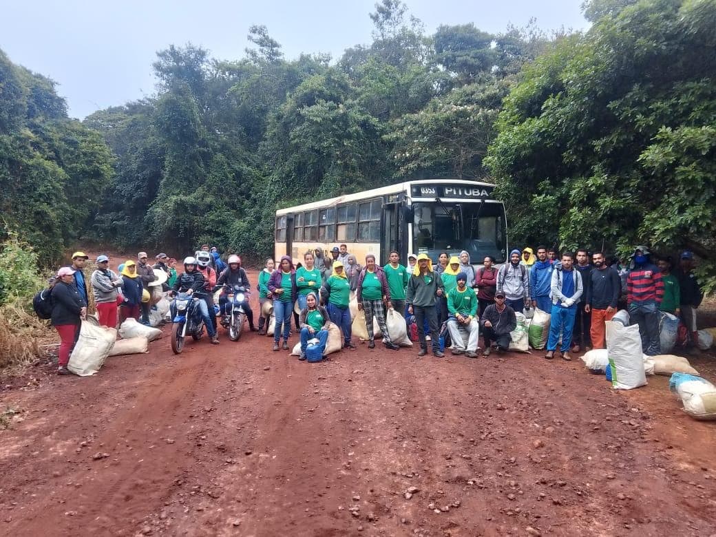 Equipe de cooperados da AGROCOOP Sertão reunida ao lado do ônibus na estrada da lavoura
